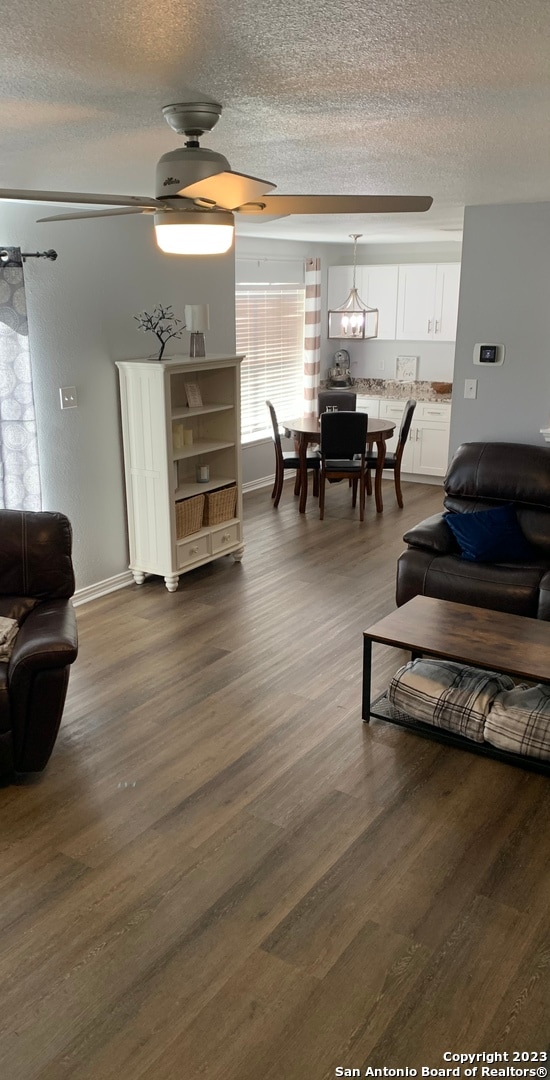 living room featuring a textured ceiling, dark hardwood / wood-style flooring, and ceiling fan