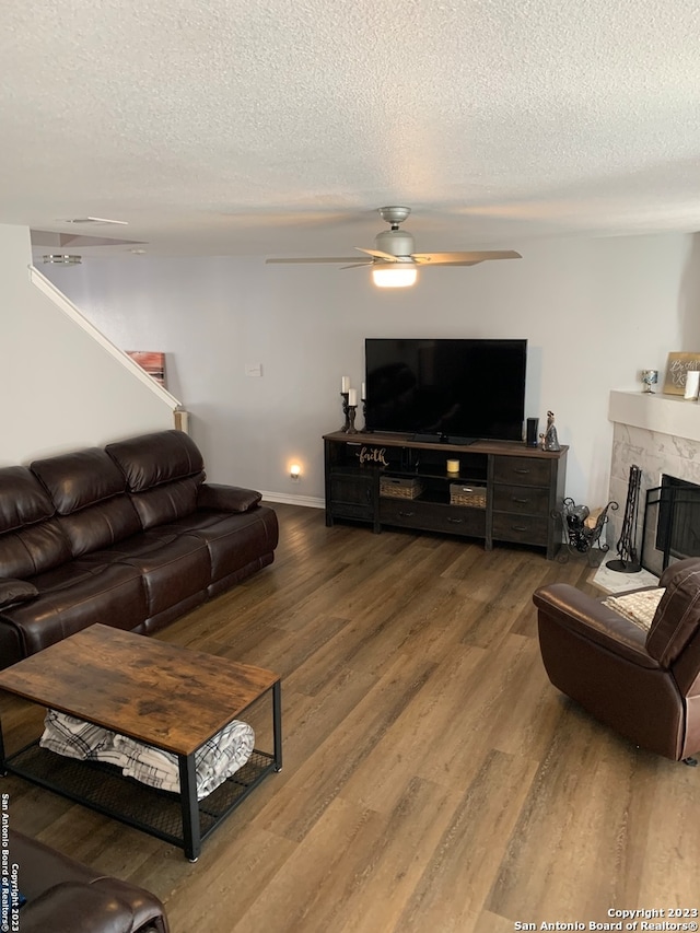 living room featuring a textured ceiling, hardwood / wood-style flooring, ceiling fan, and a premium fireplace