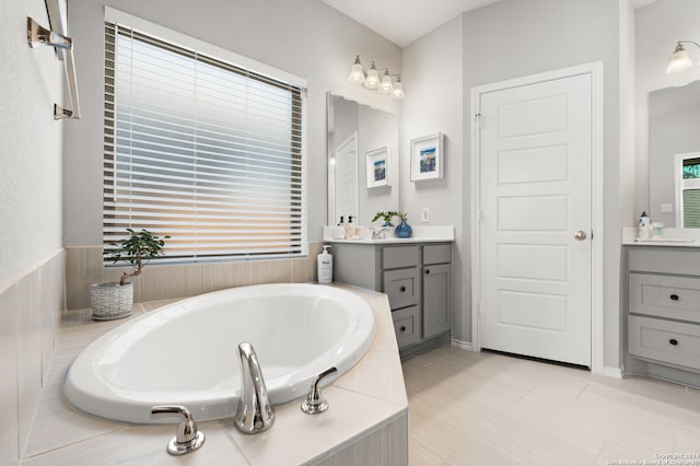 bathroom with tile patterned floors, vanity, plenty of natural light, and a relaxing tiled tub