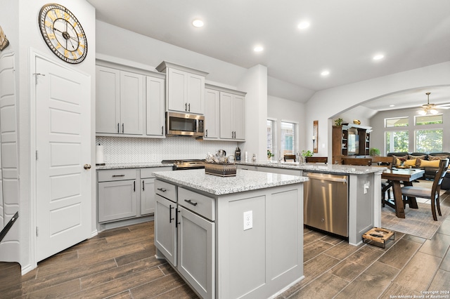 kitchen featuring kitchen peninsula, appliances with stainless steel finishes, gray cabinetry, dark wood-type flooring, and a center island