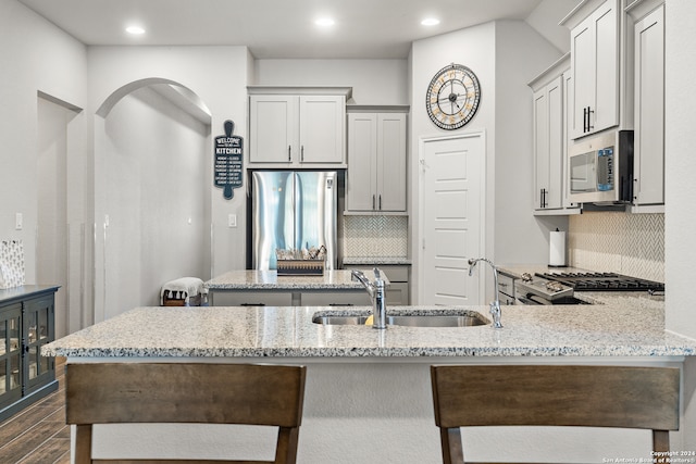 kitchen featuring dark wood-type flooring, sink, decorative backsplash, appliances with stainless steel finishes, and light stone counters