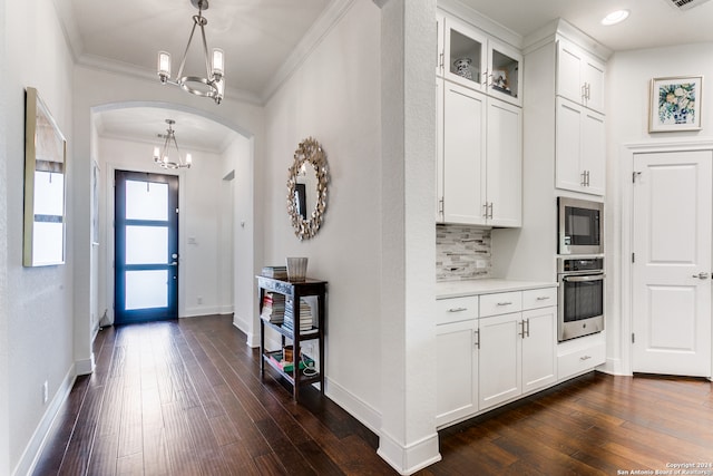 foyer entrance with dark hardwood / wood-style flooring, an inviting chandelier, and crown molding