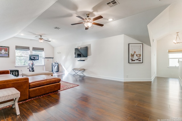 living room featuring ceiling fan with notable chandelier, vaulted ceiling, a wealth of natural light, and dark wood-type flooring