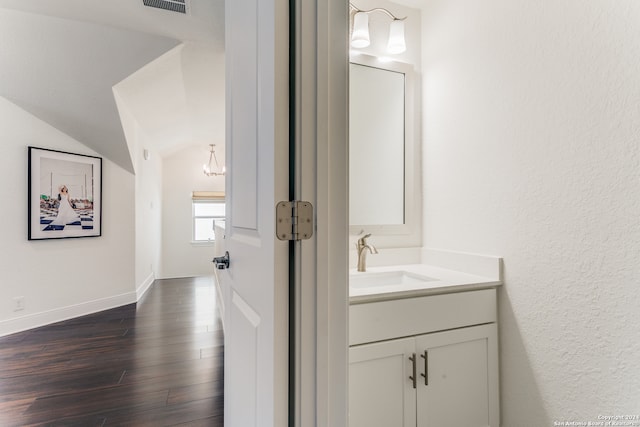 bathroom with vanity, wood-type flooring, and lofted ceiling