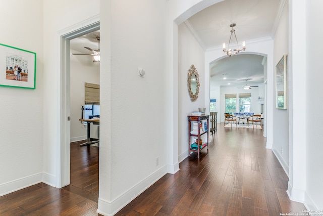 hall featuring a chandelier, dark wood-type flooring, and ornamental molding