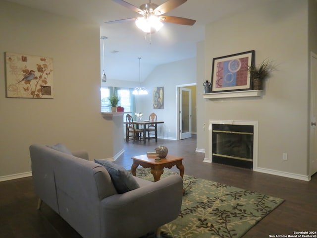 living room featuring lofted ceiling, dark wood-type flooring, and ceiling fan with notable chandelier