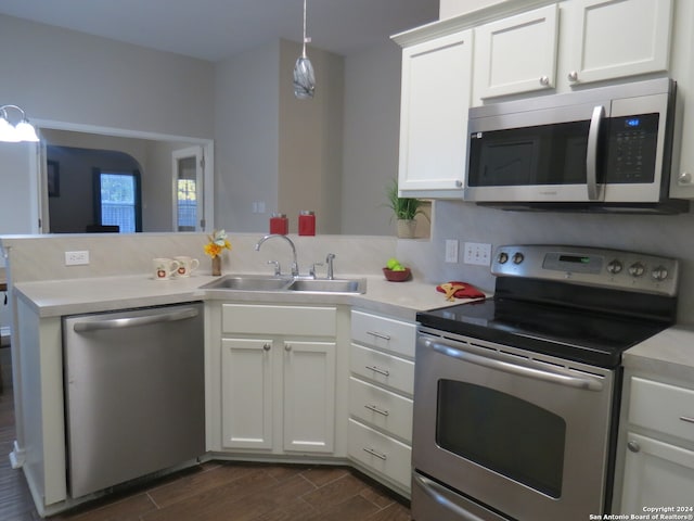 kitchen featuring dark wood-type flooring, sink, appliances with stainless steel finishes, white cabinetry, and kitchen peninsula