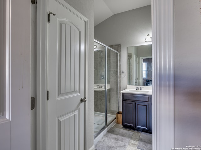 bathroom with vanity, a shower with shower door, and vaulted ceiling