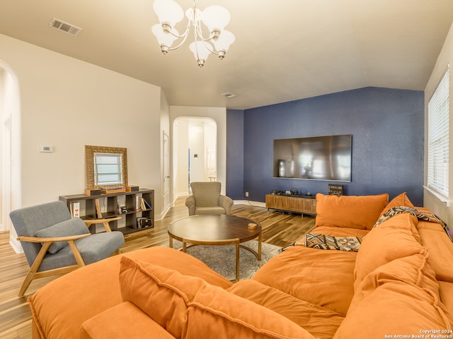 living room featuring a chandelier, light hardwood / wood-style floors, and vaulted ceiling