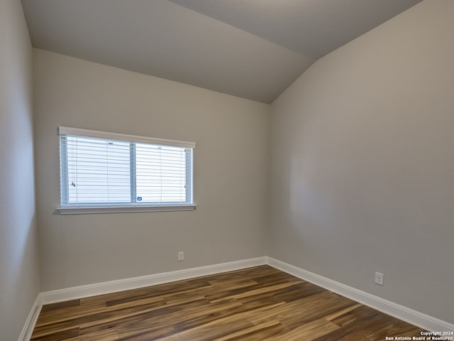 empty room with lofted ceiling and dark wood-type flooring