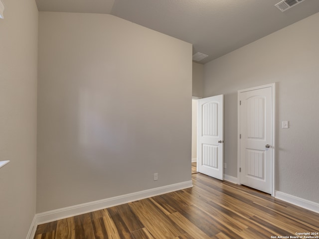 unfurnished room featuring dark hardwood / wood-style floors and vaulted ceiling