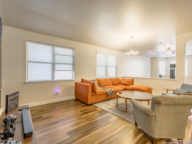 living room with ceiling fan with notable chandelier, dark hardwood / wood-style floors, and plenty of natural light