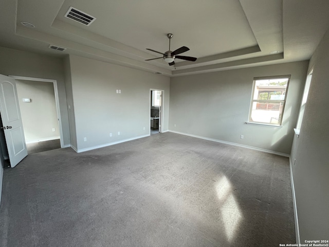 carpeted empty room with a raised ceiling and ceiling fan