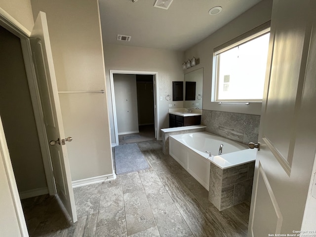 bathroom featuring hardwood / wood-style floors, vanity, and tiled tub