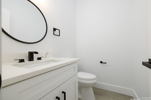 bathroom with hardwood / wood-style floors, vanity, and toilet