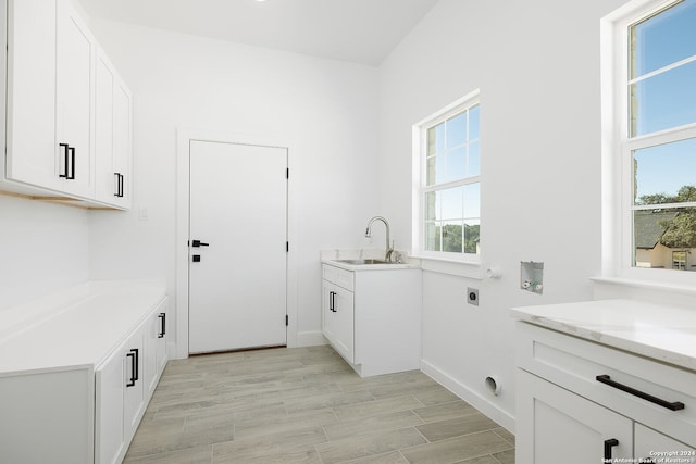 washroom with sink, cabinets, washer hookup, hookup for an electric dryer, and light hardwood / wood-style floors