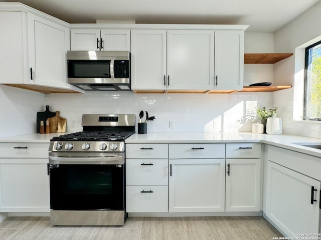 728 Rittiman, Terrell Hills, TX 78209 - kitchen with stainless steel appliances, white cabinetry, open shelves, light countertops, and decorative backsplash
