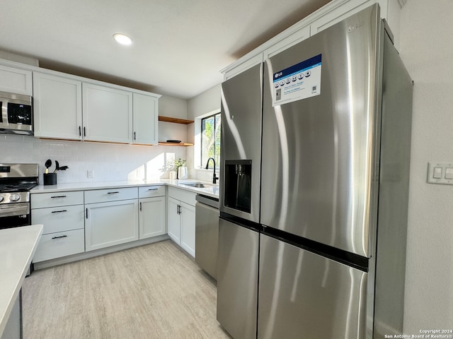 kitchen featuring decorative backsplash, sink, white cabinets, and stainless steel appliances