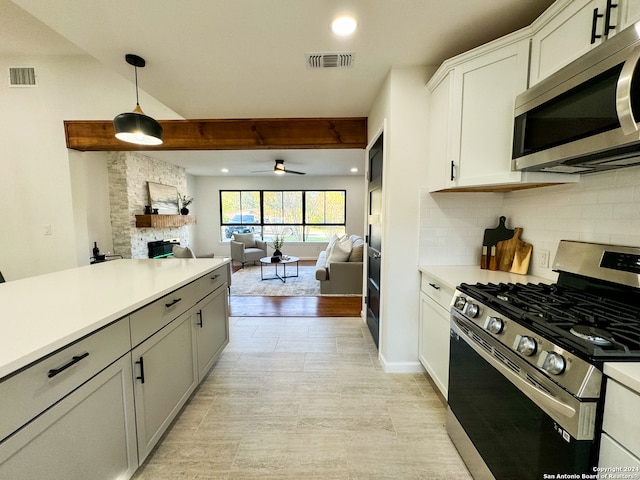 kitchen featuring ceiling fan, hanging light fixtures, stainless steel appliances, tasteful backsplash, and a fireplace