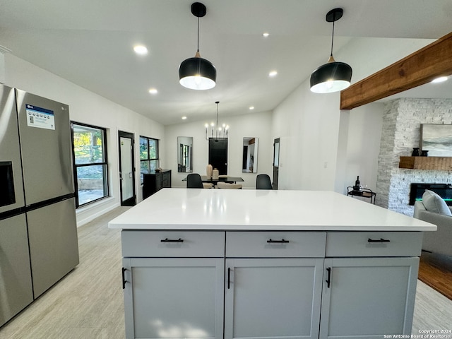 kitchen featuring lofted ceiling, an inviting chandelier, stainless steel refrigerator with ice dispenser, hanging light fixtures, and a fireplace