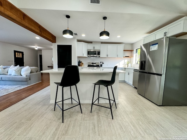 kitchen with white cabinets, pendant lighting, appliances with stainless steel finishes, and light hardwood / wood-style flooring