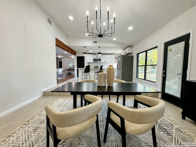 dining space with a notable chandelier, light hardwood / wood-style floors, and lofted ceiling