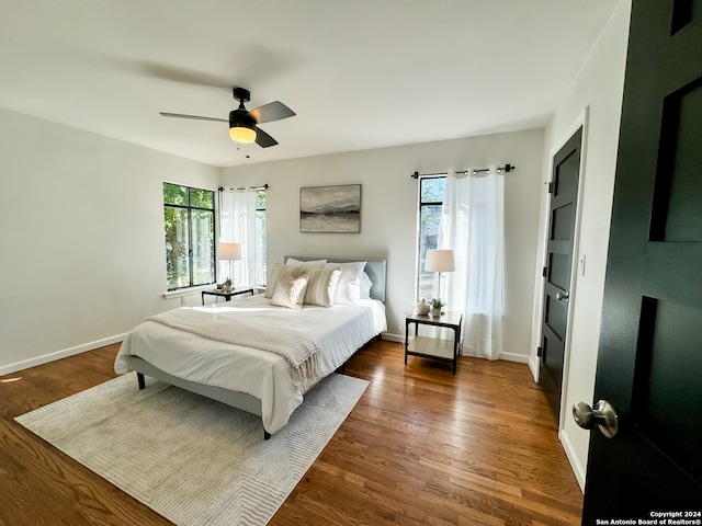 bedroom featuring multiple windows, dark hardwood / wood-style flooring, and ceiling fan