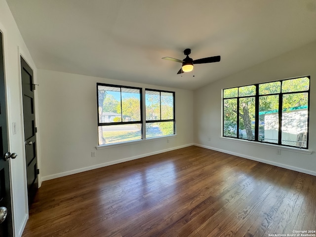 empty room with ceiling fan, dark hardwood / wood-style flooring, and vaulted ceiling