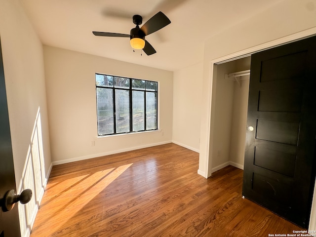 unfurnished bedroom with ceiling fan, a closet, and wood-type flooring