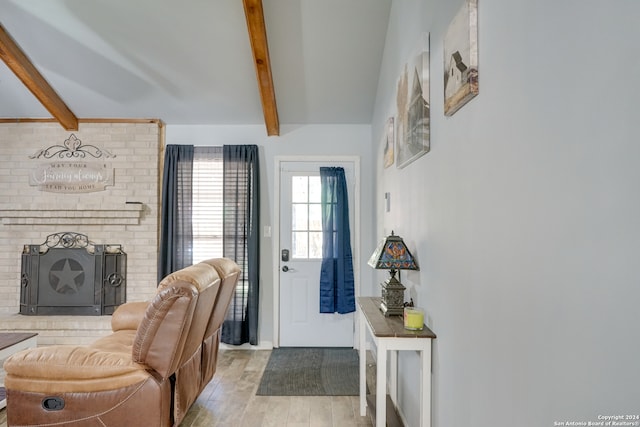 entrance foyer featuring a fireplace, light hardwood / wood-style floors, and beamed ceiling