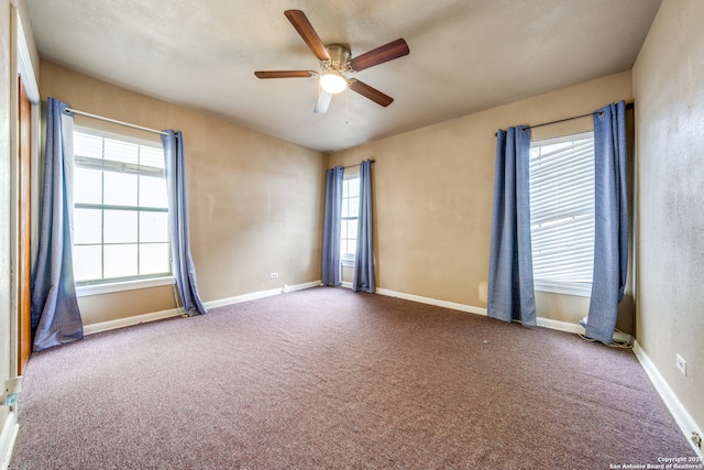 carpeted empty room featuring ceiling fan and a wealth of natural light