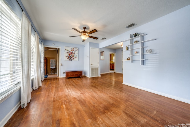 unfurnished living room with ceiling fan, a textured ceiling, and hardwood / wood-style flooring