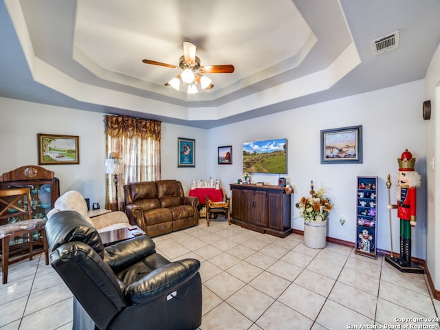 tiled living room featuring ceiling fan and a tray ceiling