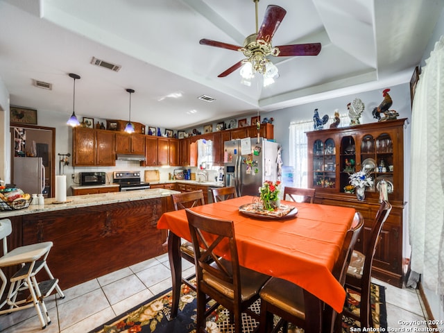 tiled dining space featuring a raised ceiling, ceiling fan, and sink