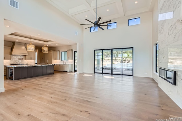 unfurnished living room featuring a tile fireplace, a high ceiling, light hardwood / wood-style flooring, and ceiling fan