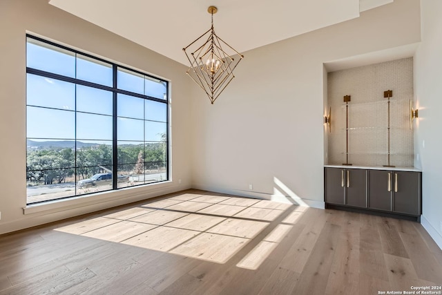 unfurnished dining area featuring a chandelier and light wood-type flooring