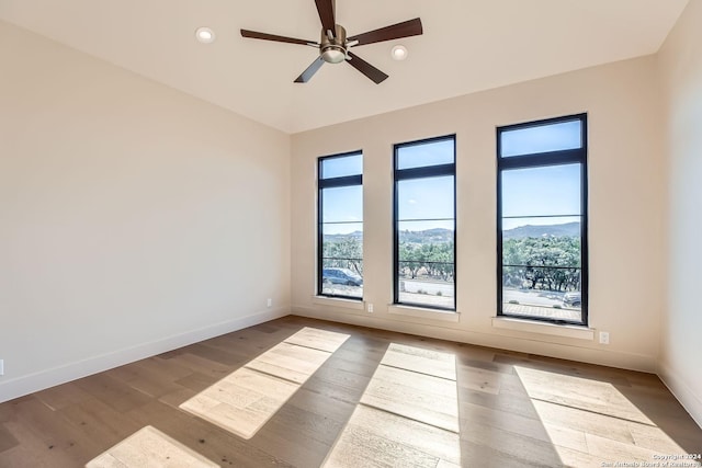 unfurnished room with ceiling fan, hardwood / wood-style floors, and a mountain view