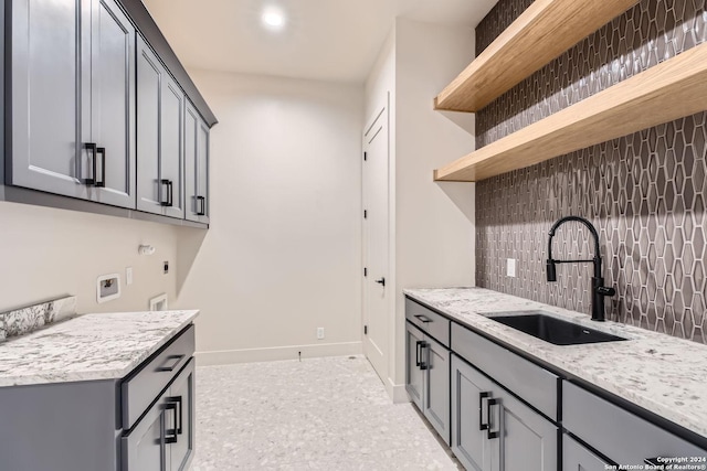 kitchen featuring backsplash, gray cabinets, light stone countertops, and sink