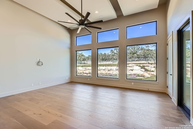 spare room featuring ceiling fan, a towering ceiling, and light hardwood / wood-style flooring