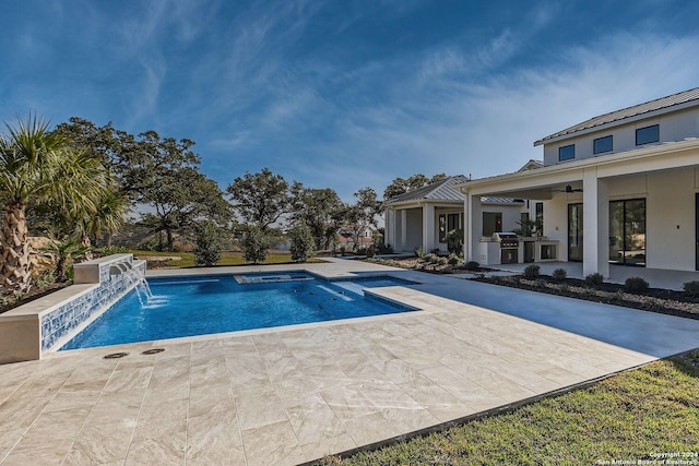 view of pool with pool water feature, ceiling fan, a patio area, and exterior kitchen