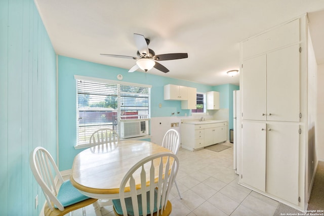 tiled dining area featuring ceiling fan and wood walls