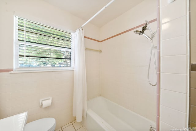 bathroom with tile patterned floors, toilet, tile walls, and shower / tub combo