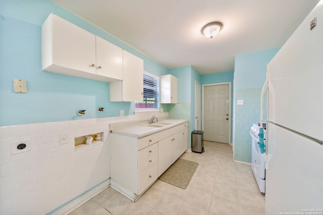 kitchen with white appliances, white cabinets, sink, light tile patterned floors, and tile walls