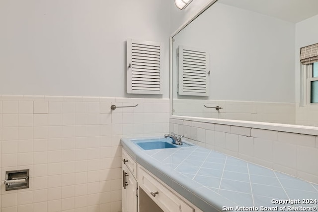 bathroom featuring vanity and tile walls