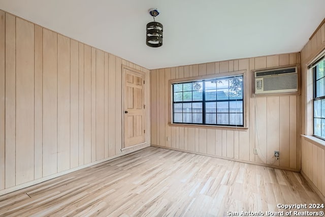 spare room featuring light hardwood / wood-style floors, a wall mounted AC, and wood walls