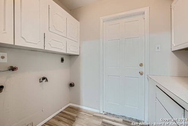 washroom featuring electric dryer hookup, cabinets, and light wood-type flooring