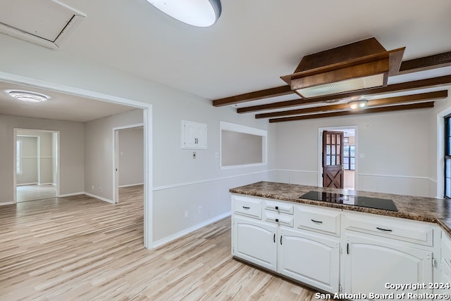 kitchen featuring white cabinetry, beamed ceiling, dark stone countertops, light hardwood / wood-style floors, and black electric stovetop