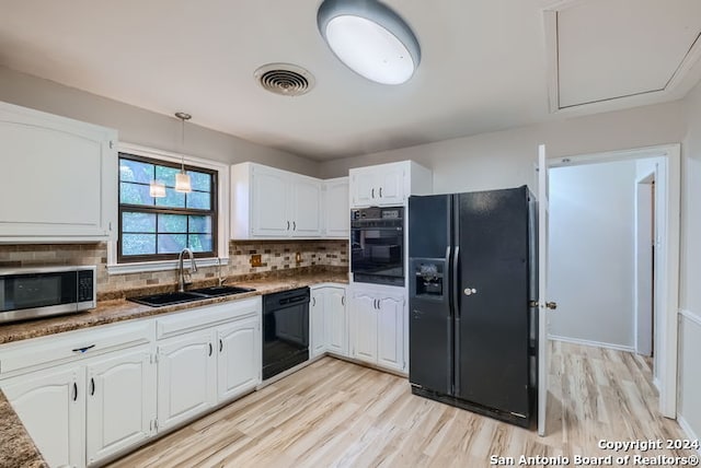 kitchen featuring pendant lighting, sink, white cabinetry, and black appliances