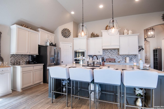 9104 Pepperton Ln, San Antonio, TX 78254 - kitchen with backsplash, appliances with stainless steel finishes, an island with sink, vaulted ceiling, and white cabinets
