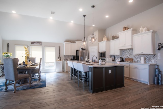9104 Pepperton Ln, San Antonio, TX 78254 - kitchen with appliances with stainless steel finishes, a kitchen island with sink, a kitchen bar, backsplash, and white cabinets